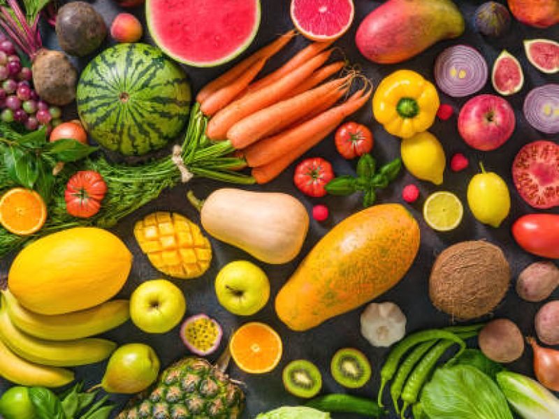 Colorful raw fruits and vegetables varied vegan food, vivid rainbow arrangement full frame background